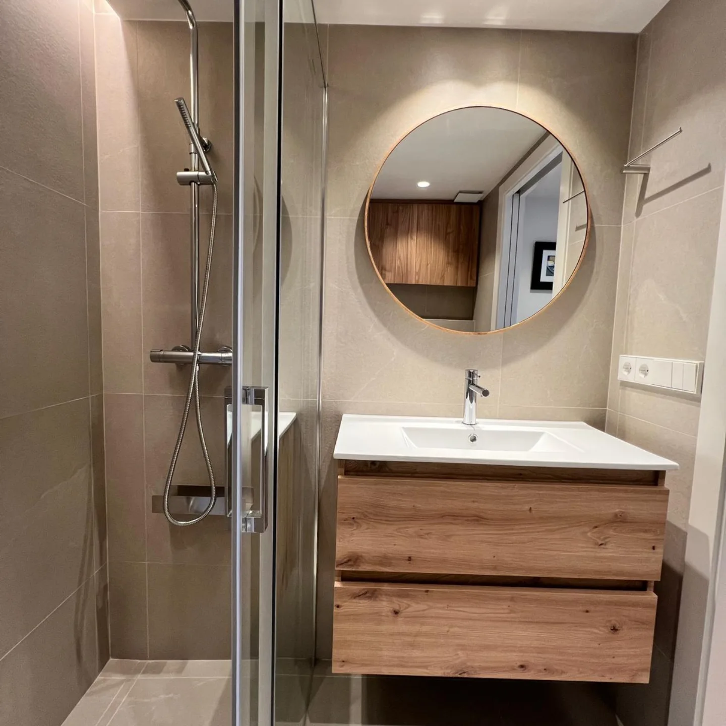 Baño moderno con espejo redondo iluminado y ducha