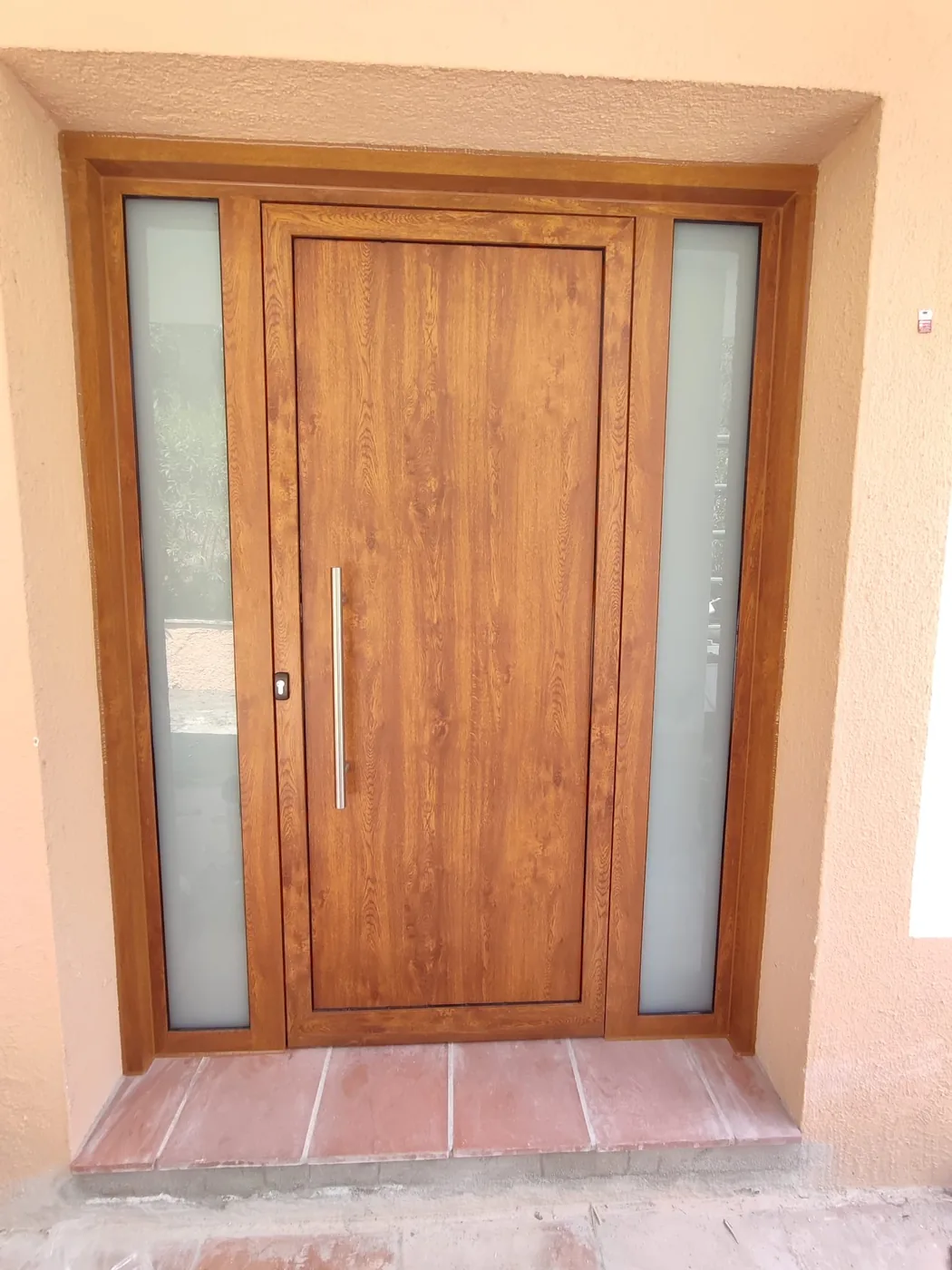 Puerta de entrada con acabado efecto madera y vidrio lateral
