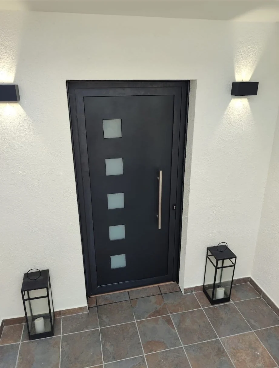 Puerta de entrada negra con iluminación exterior